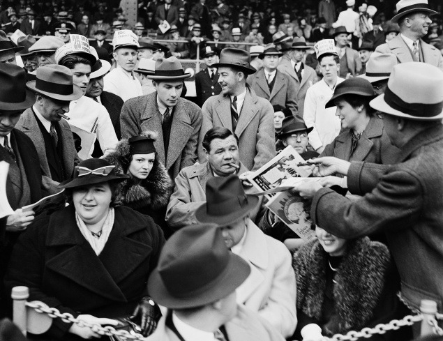30. september 1936: Baseballovej legende Babe Ruthovi (muž s cigarou v ústach) podávajú program počas prvého zápasu Svetovej série. Sprevádza ho jeho druhá manželka Clare (vľavo) a speváčka Kate Smith (vpredu vľavo).