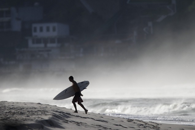 Surfer vychádza z vody na pláži Barra da Tijuca v brazílskom Rio de Janeiro.