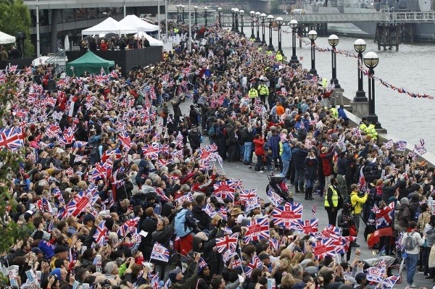 Ľudia mávajú vlajkami na počesť kráľovnej Alžbety II.
