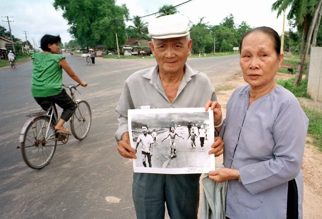Phan Thanh Tung a jeho žena Du Ngoc Nu, rodiča Kim Phuc, držia fotografiu na ulici, kde bol záber kedysi urobený.