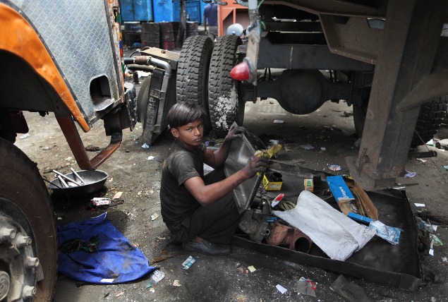 Chlapec čistí autosúčiastky v indickom Nai Dillí.