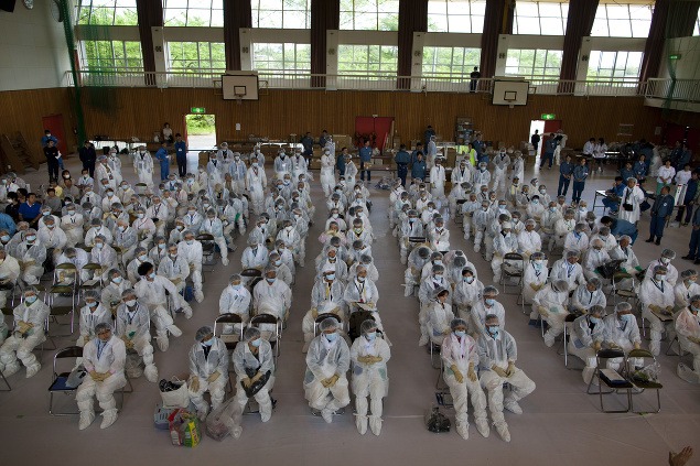 Evakuovaní v maskách a ochranných oblekoch sa zhromaždili v telocvični v japonskom Hirono.