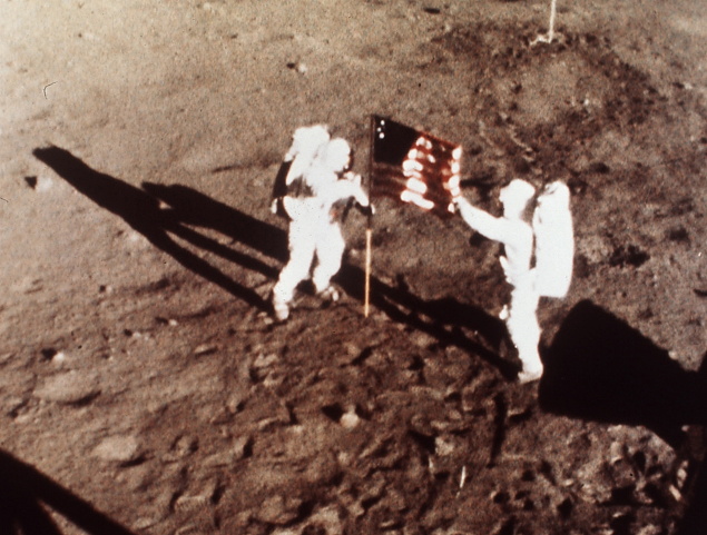 Neil Armstrong a Edwin Aldrin umiestňujú americkú vlajku na mesačný povrch.