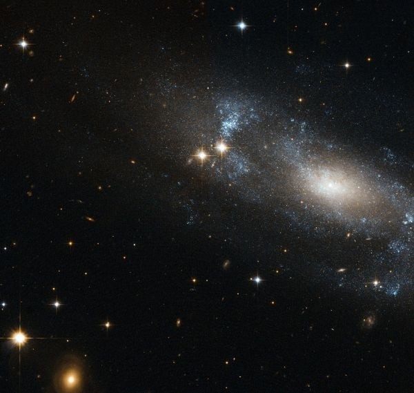 Špirálová galaxia ESO 499-G37, ktorej ramená možno pozorovať ako modrasté oblasti krúžiace okolo jadra