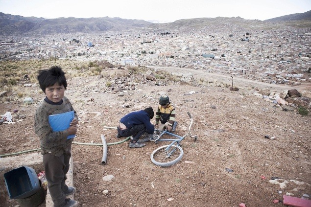 Bratia sa pokúšajú opraviť koleso na bicykli. Aj napriek tomu, že pracujú v bani, sú to stále deti s potrebou hrať sa.