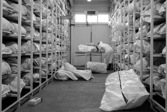 Patológ odhaľuje jedno zo 4.000 vriec s pozostatkami zavraždených vo vnútri obrej chladničky v Tuzle, 1. júl 2004.