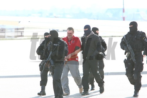 Bratislava, 12:45: Mišenku kukláči vyvádzajú z vládneho špeciálu s putami na rukách. 
