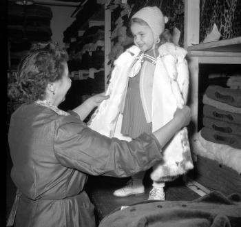 Malá Marika si skúša detský kožuštek v sklade kožušín bratislavského Veľkoobchodu s odevným tovarom. (1956)