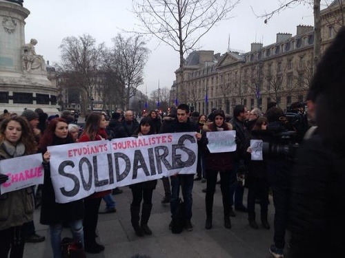 Študenti žurnalistiky držia v uliciach na znak smútku nápis 