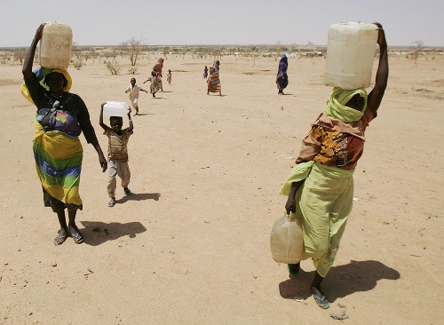 Ženy odnášajú vodu do utečeneckého tábora v blízkosti mesta Iriba vo východnom Čade. Boje medzi povstalcami a sudánskou armádou sa začali v Darfúre v roku 2003, táto fotografia pochádza z 25. septembra 2004. V púšti čelilo 2,7 milióna ľudí obrovskej humanitárnej kríze.