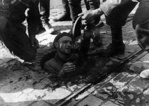 Nemeckí vojaci počas povstania vyťahujú Žida z kanála 