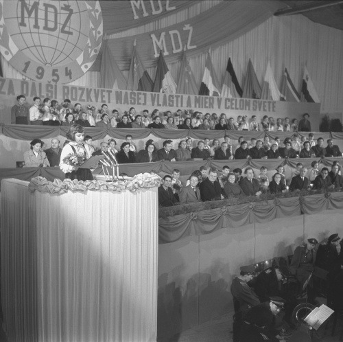 Veľtržný palác v Bratislave zaplavili tisícky žien, mnohé z nich prišli na manifestáciu priamo od svojich strojov v závodoch, z obchodov a úradov. Manifestáciu prišli pozdraviť aj pionieri cvičnej školy v Bratislave. (9. marca 1954)
