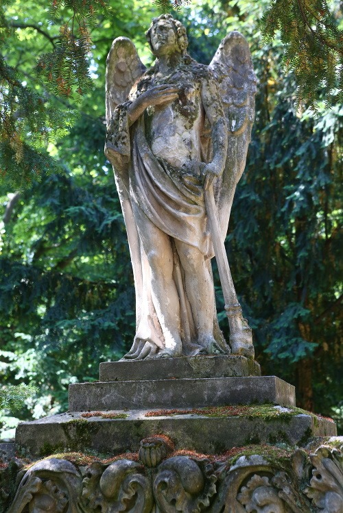 Postava smútiaceho anjela so zhasínajúcou pochodňou otočenou smerom k zemi. Kamenná dekoratívna rímsa pod sochou s motívom makovíc – symbol spánku. 