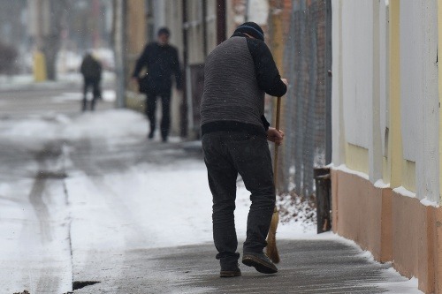 Pán zametá sneh zo zasneženého chodníka pred Galériou Jána Koniarka v Trnave 