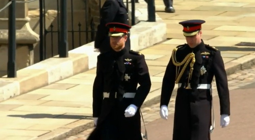 Princ Harry s bratom a zároveň aj svadobným svedkom Williamom prichádzajú do kaplnky. Obaja majú oblečené čierne vojenské uniformy. 