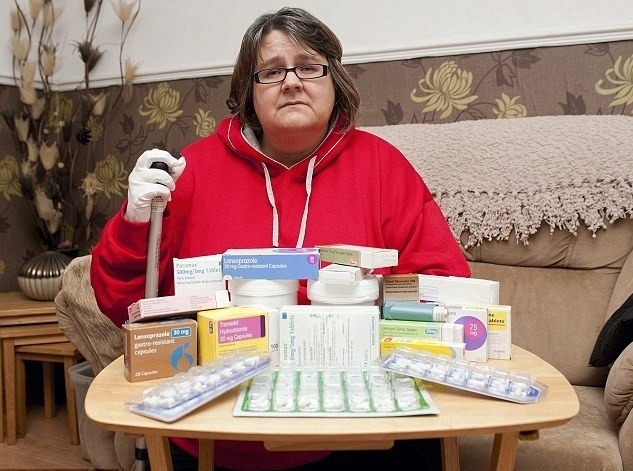 Smutná Tracy obklopená množstvom liekov, ktoré musí brať. (Dailymail.co.uk)