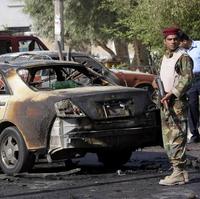Iracký policajt stojí pri aute, v ktorom odpálil atentátnik výbušninu v meste Basra.