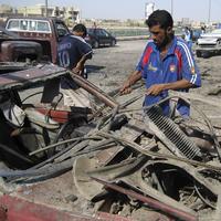 Muž si berie súčiastky z vybuchnutého auta v Bagdade.