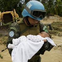 Člen brazílskej záchranárskej jednotky na Haiti odnáša dieťa z oblasti postihnutej tropickou búrkou.