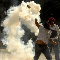 Jeden z protestujúcich študentov hádže nádobu so slzným plynom späť k policajtom.