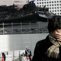 Nešťastná žena plače pred zhorenou pamiatkou.