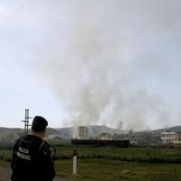 Policajt na pozerá na zdvíhajúci sa dym z miesta silnej explózie na vojenskej základni