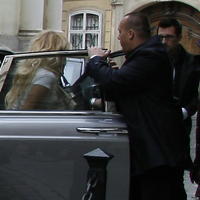 Pamela Anderson vystupuje z luxusnej limuzíny pred vchodom do hotela.