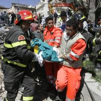 Hasiči znášajú obeť z trosiek budovy zničenej zemetrasením