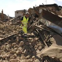 Záchranár chodí po troskách domu po silnom zemetrasení v Taliansku
