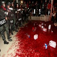 Thajskí policajti stojaci pri vyliatej krvi pred sídlom vlády