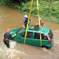 Hasiči vyťahujú auto z rozvodnej rieky