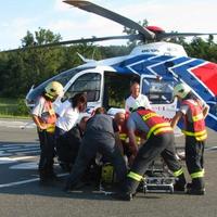 Záchranári nakladajú zraneného motorkára do vruľníka