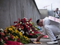 Muž zapaľuje sviečku pri pamätníku Berlínskeho múru