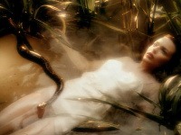 Kylie Minogue vo videoklipe k piesni Where the Wild Roses Grow leží na hladine jazera.  
