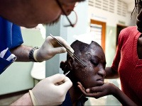 Magna lekár ošetruje dievča so zranenou tvárou ako následok zemetrasenia, Haiti 2010.