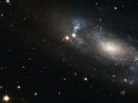 Špirálová galaxia ESO 499-G37, ktorej ramená možno pozorovať ako modrasté oblasti krúžiace okolo jadra