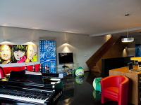 V obývacej miestnosti vily sa okrem pohodlných kresiel a sedačiek nachádza aj luxusné čierne piano, ktoré spevákom pomôže pri skúšaní skladieb.