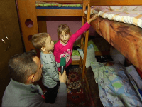 Vilo Rozboril s deťmi v izbe zaplnenej posteľami. 