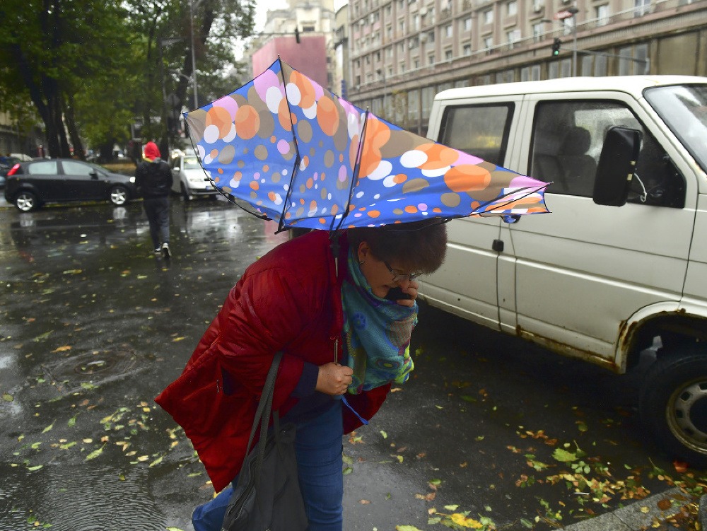 Žena s dáždnikom prechádza po ulici 24. októbra 2017 v Bukurešti. 