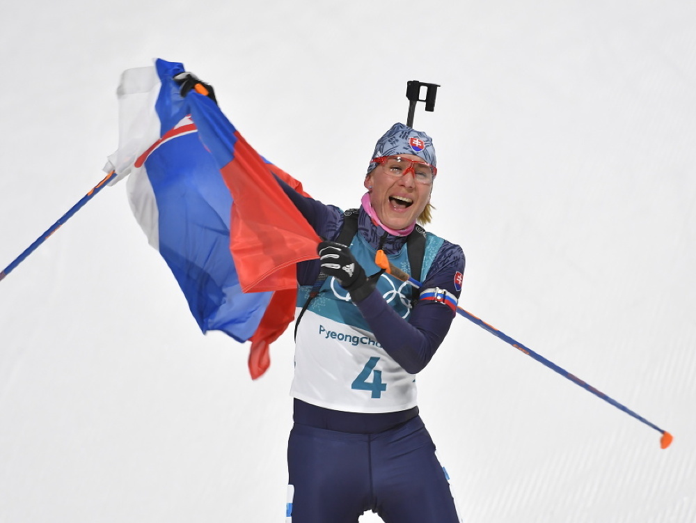 Anastasia Kuzminová drží slovenskú vlajku v cieli po zisku zlatej olympijskej medaily počas pretekov žien s hromadným štartom na 12,5 km