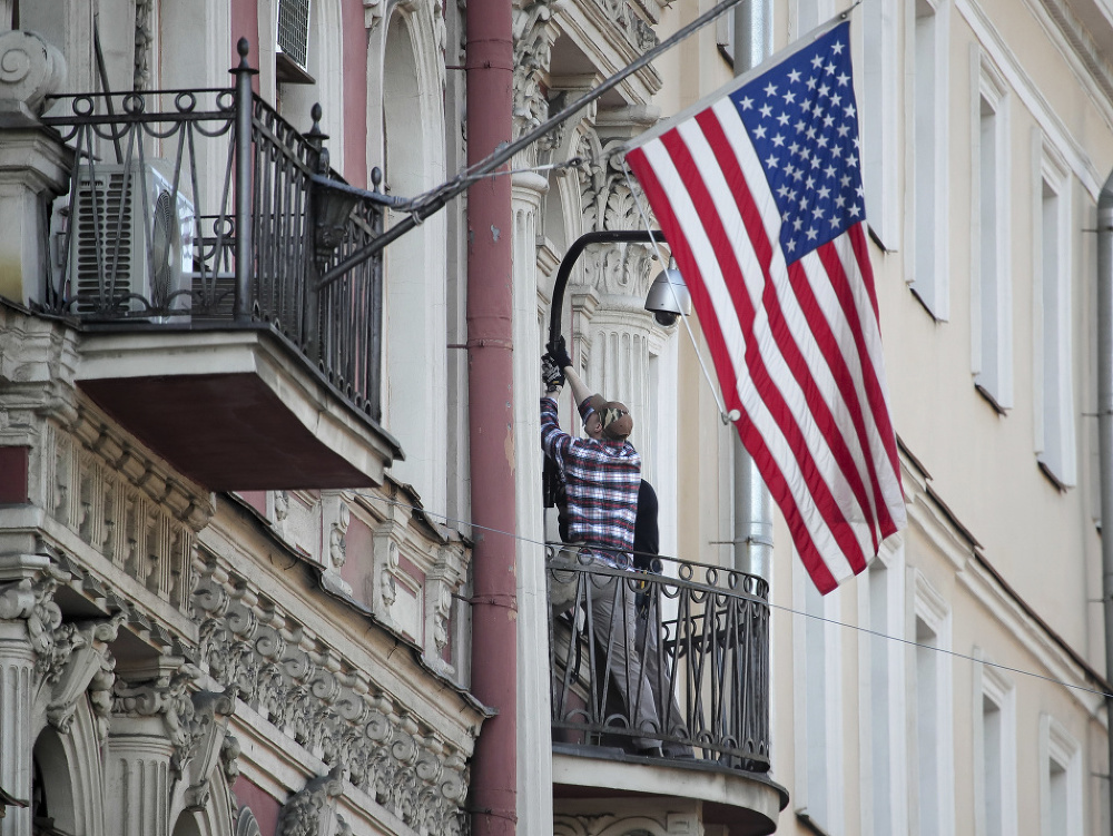 Muž skladá americkú zástavu z budovy konzulátu v Petrohrade.