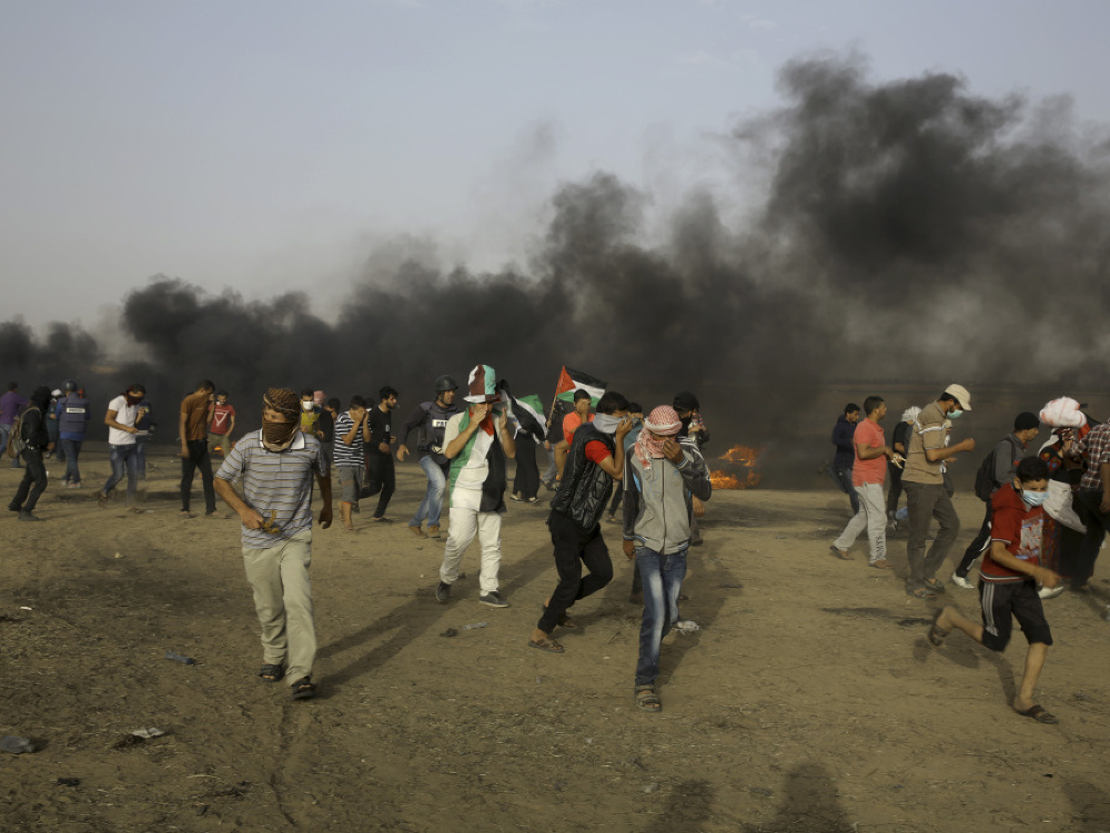 Palestínski protestujúci utekajú z miesta bojov v Pásme Gazy.