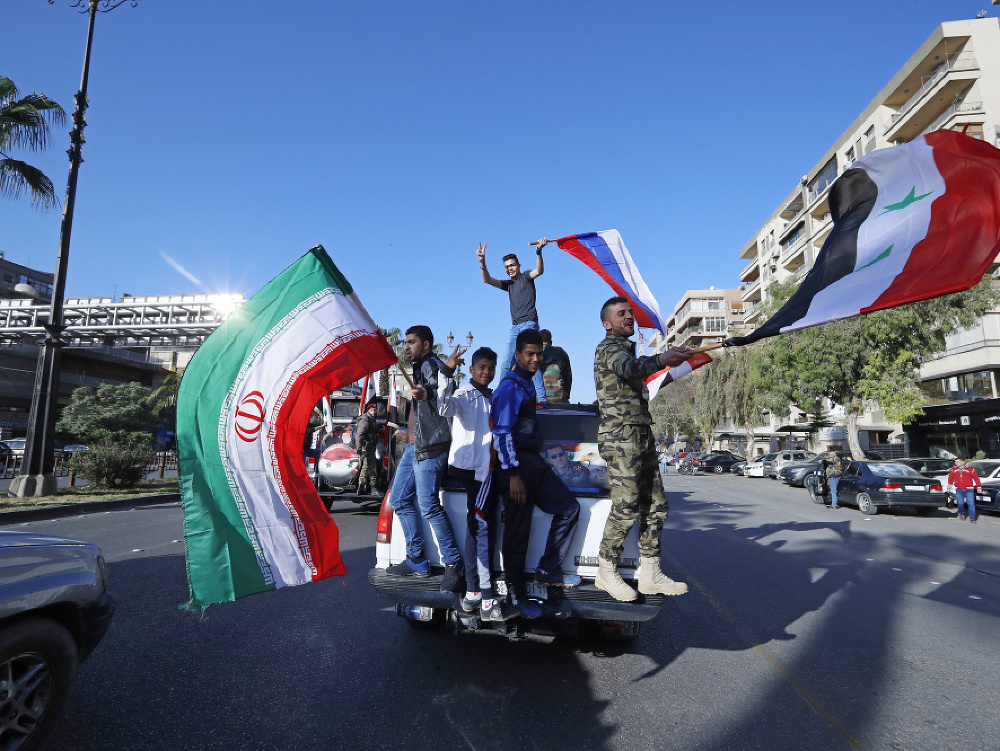 Sýrski vojaci mávajú vlajkami na protest proti USA.