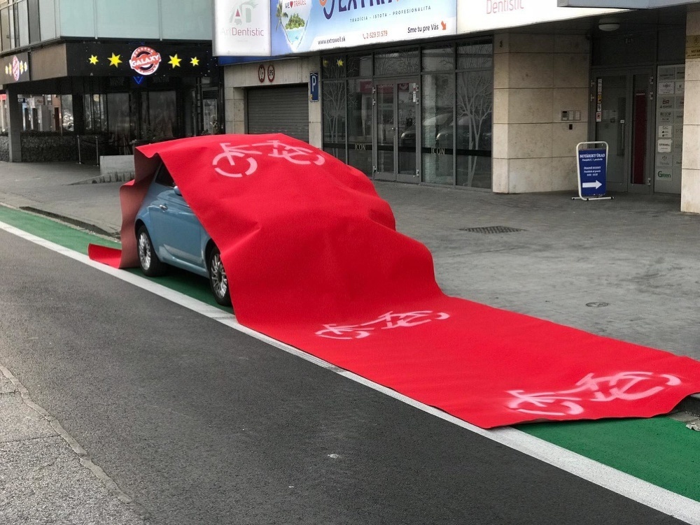 Červený koberec na vozidle, ktoré bolo zaparkované na cyklochodníku. 
