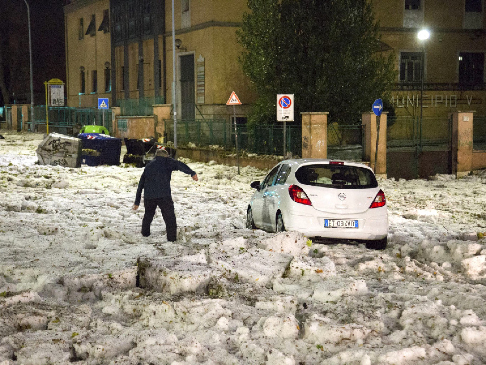 Muž sa snaží dostať k autu po zľadovatenej ceste po krupobití v Ríme