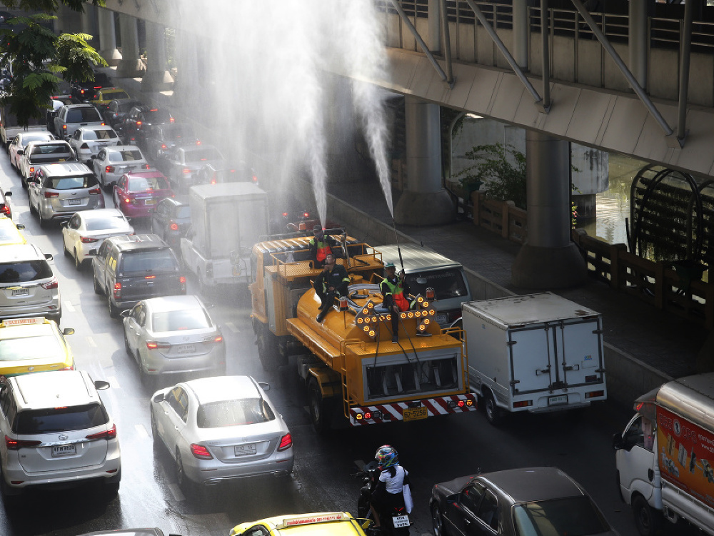 Na snímke cestári rozprašujú vodu z vodného dela počas hustého smogu