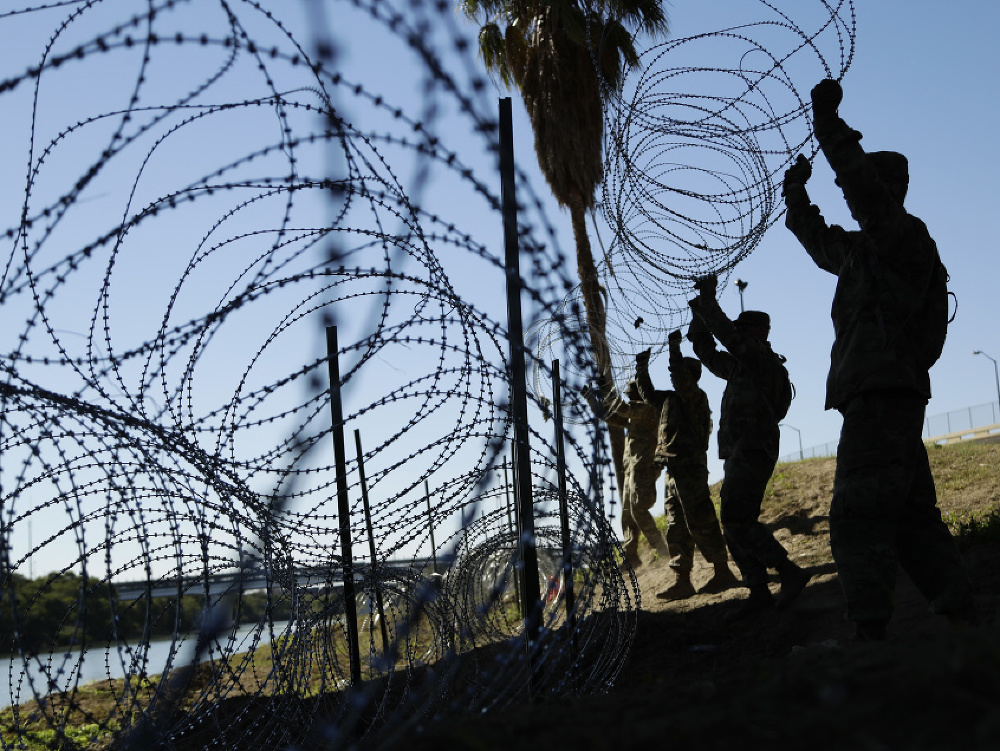 Americký vojaci na hranici naťahujú ostnatý drôt. 