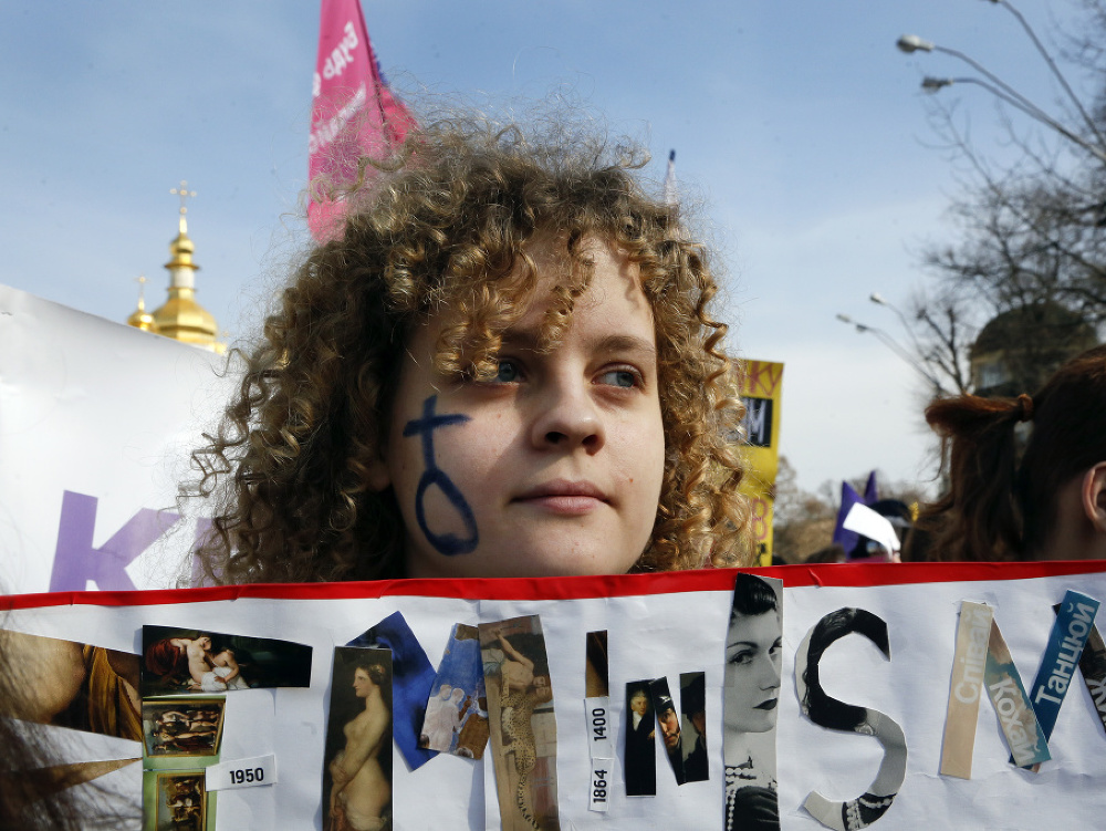 Ukrajinská žena pochoduje s transparentom počas Medzinárodného dňa žien v Kyjeve