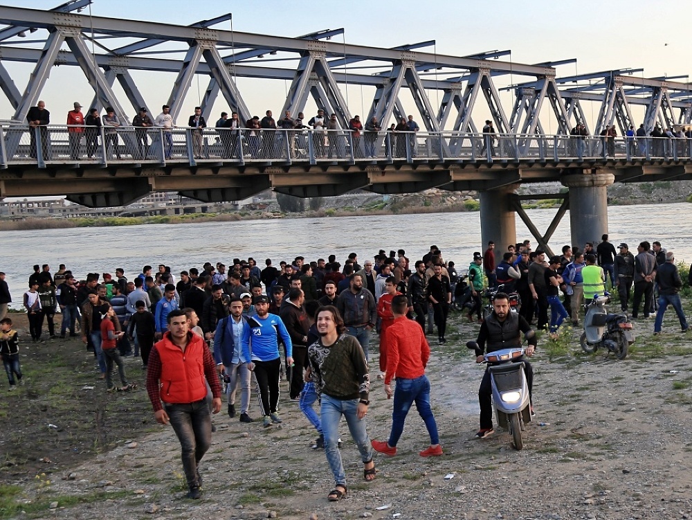 Ľudia v okolí potopenej lode na rieke Tigris