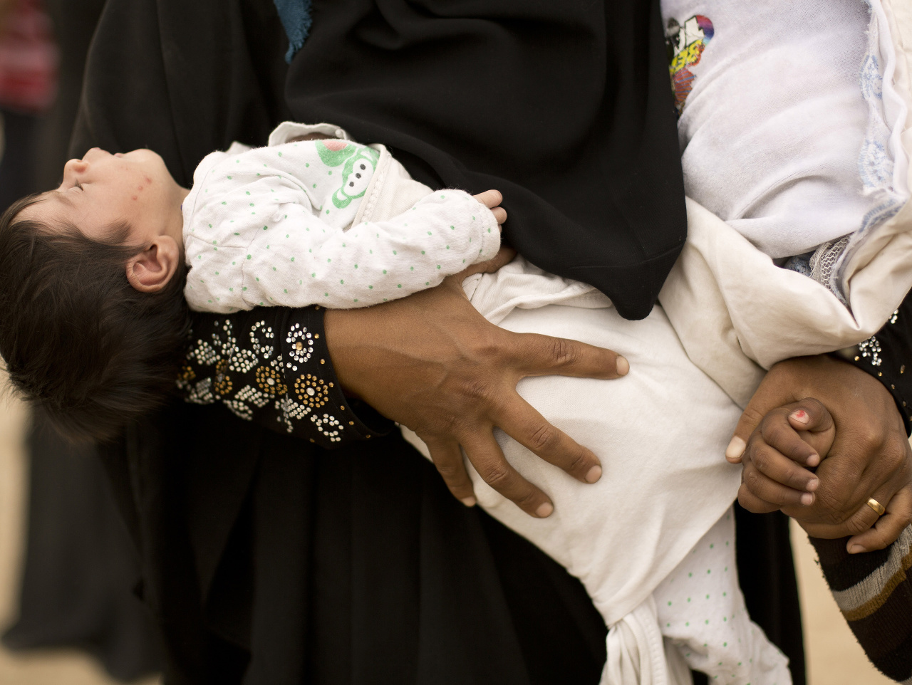 Na archívnej snímke z 18. apríla 2017 žena drží novorodené dieťa v jednej ruke počas úteku z Mósulu. 